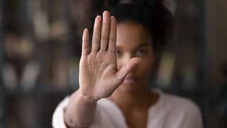 Imagem mostra uma mulher negra que está com a mão levantada