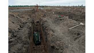 Foto de 22 de maio mostra caixão sendo colocado em túmulo do cemitério no assentamento de Staryi Krym, nos arredores de Mariupol