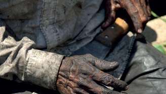 Imagem mostra mãos de um homem negro que segura um facão