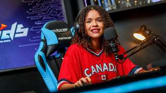 Foto mostra a streamer de games Taiane Silva, uma mulher negra que usa uma blusa vermelha com a palavra "Canadá".