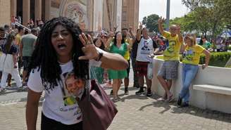 Imagem mostra mulher negra com a camisa de Lula em frente ao Santuário Nacional de Nossa Senhora Aparecida. Ao fundo, apoiadores de Jair Bolsonaro fazem o