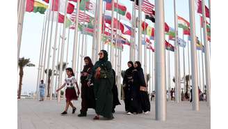 Mulheres caminham pela praça das bandeiras em Doha