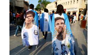 Torcedores argentinos carregam bandeiras com imagens dos ídolos Diego Maradona e Lionel Messi na terça-feira, 13, no Catar.