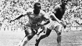 Na imagem, Pelé, um jogador negro, driblando durante um jogo de futebol Tarcisio Burgnich, jogador branco. Foto em preto e branco, estão em um estádio de futebol, na final da Copa de 1970, no México.