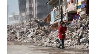 Mulher observa destroços do que costumava a ser sua casa em cidade da Turquia