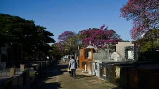 Imagem mostra homem de costas caminhando em cemitério.