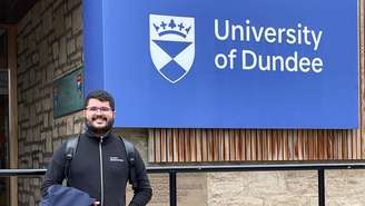 Dener Silva Miranda em frente ao logotipo da Universidade de Dundee, na Escócia, onde ele estudou pelo programa Ciência Sem Fronteiras