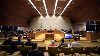 Imagem mostra uma sessão no Supremo Tribunal Federal, uma grande sala com os ministros sentados no centro e outros espectadores em sua volta.