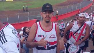 Imagem mostra Rafael Garcia nas arquibancadas do estádio Cícero Pompeu de Toledo rodeado de torcedores do São Paulo. O jovem usa boné preto, óculos de grau e uma camisa do time de futebol.