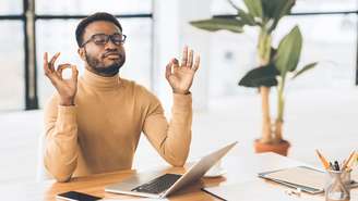 Imagem meramente ilustrativa de um homem meditando na mesa de trabalho