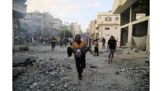 Homem palestino carrega criança após ofensiva israelense contra palestinos na Faixa de Gaza