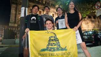 Membros do grupo Pibes Libertarios mostram uma bandeira de Gadsden, símbolo do libertarianismo