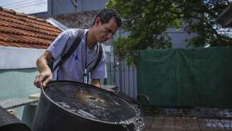 Agente de saúde retira água parada no quintal de casa em São Caetano, na Grande São Paulo