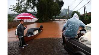 Pessoas resgatam seus pertences perto de área alagada próxima ao rio Taquari durante fortes chuvas na cidade de Encantado, no Rio Grande do Sul