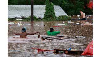 Pessoas andam em área alagada perto do Rio Taquari em Encantado, no Rio Grande do Sul