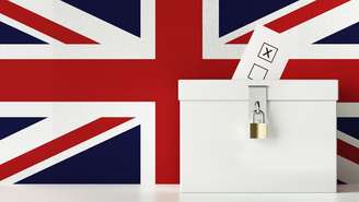 Urna de votação com a bandeira do Reino Unido ao fundo