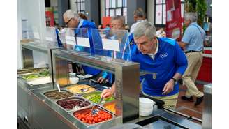 O presidente do Comitê Olímpico Internacional, Thomas Bach, faz refeição no refeitório dos atletas na Vila Olímpica, em Paris