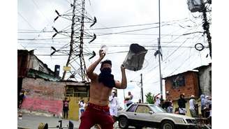 Um homem segura um tanque de metal enquanto moradores batem panelas para protestar contra os resultados das eleições depois que o presidente Nicolás Maduro e seu rival da oposição Edmundo Gonzalez reivindicaram a vitória na eleição presidencial de domingo, no bairro de Los Magallanes de Catia, em Caracas, Venezuela , em 29 de julho de 2024.