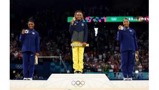 Medalhista de ouro Rebeca Andrade, do Brasil, comemora no pódio com a medalhista de prata Simone Biles, dos EUA, e a medalhista de bronze, Jordan Chiles, também dos EUA