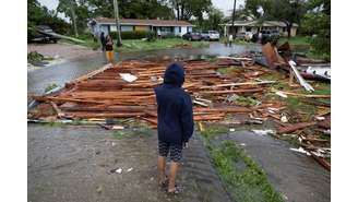 Um homem olha para um telhado na rua de uma casa próxima depois que um tornado atingiu a área enquanto o furacão Milton se aproximava de Fort Myers, Flórida, EUA, em 9 de outubro de 2024.