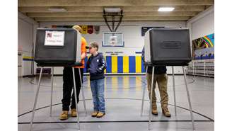 Um menino observa seu pai votando para a eleição presidencial dos EUA de 2024, no dia da eleição em Asheville, Carolina do Norte, EUA, 5 de novembro de 2024. 