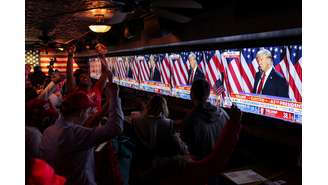 Apoiadores do candidato presidencial republicano, ex-presidente dos EUA, Donald Trump, reagem ao lado de telas que mostram Trump falando no Centro de Convenções do Condado de Palm Beach, enquanto participam da festa de observação do New York Young Republican Club durante a eleição presidencial dos EUA de 2024, em Manhattan, Nova York, EUA, 6 de novembro de 2024. 