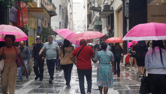 Pedestres se protegem da chuva na região central de São Paulo, na tarde desta quarta- feira (6).