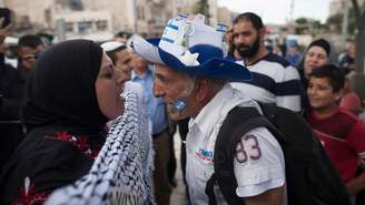 Uma mulher palestina usando um lenço na cabeça e um homem israelense usando um chapéu azul e branco com a bandeira israelense gritam um com o outrodicas para apostar sportingbetJerusalém