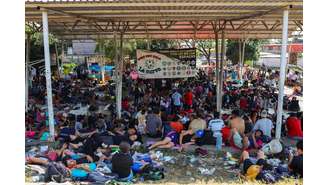 Migrantes aguardam em uma quadra de esportes por caravana com destino à fronteira norte entre Estados Unidos e México, na cidade de Huixtla