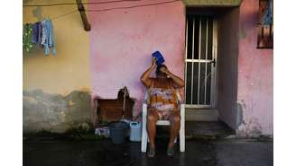 Uma mulher se refresca do lado de fora de sua casa durante a onda de calor em Guaratiba, no subúrbio do Rio de Janeiro, nesta segunda-feira, 17