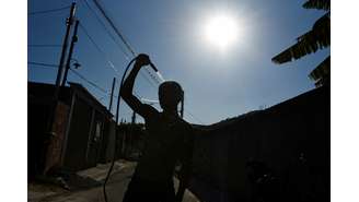 Um homem se refresca com uma mangueira na rua durante uma onda de calor em Guaratiba, no subúrbio do Rio de Janeiro, Brasil, 17 de fevereiro de 2025