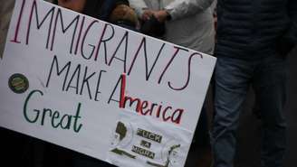 Cartaz diz "imigrantes fazem América grande", durante protestos anti-Trump em 18/01/25, em Washington.