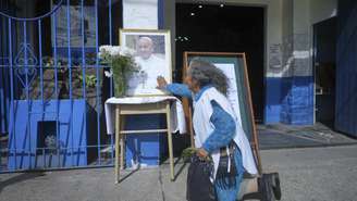 Uma mulher se ajoelha diante de um retrato do falecido papa Francisco na Paróquia de Caacupe, que ele frequentemente visitava e onde pregava, em Buenos Aires, Argentina, segunda-feira, 21 de abril de 2025.