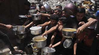 Moradores da Faixa de Gaza se aglomeram para conseguir comida em uma cozinha comunitária em Jabalia, no norte do enclave palestino, nesta segunda-feira, 19 de maio de 2025.
