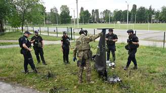 Especialistas em explosivos e policiais ucranianos examinam partes de um drone militar Shahed 136 que caiu após um ataque aéreo em Kharkiv, em 4 de junho de 2025, na Ucrânia. (Foto de SERGEY BOBOK / AFP)