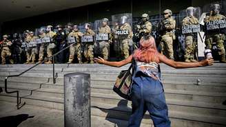 Manifestante se posiciona diante de barreira policial durante protesto em Los Angeles na segunda-feira (9).