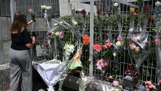 Uma aluna pendura flores na cerca da escola secundária Françoise Dolto, em Nogent, em 11 de junho de 2025, um dia após um aluno do ensino médio ter sido preso por matar uma assistente escolar de 31 anos com uma faca durante uma revista em sua mochila.