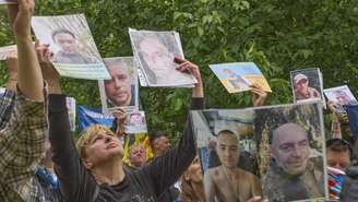 Pessoas mostram fotos de seus parentes desaparecidos a soldados ucranianos na região de Chernihiv, na Ucrânia, que retornam após uma troca de prisioneiros de guerra entre Rússia e Ucrânia.