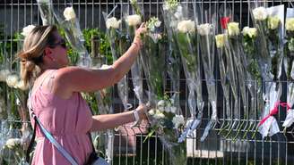 Uma mulher deposita flores em frente à escola secundária Françoise-Dolto, em Nogent, em homenagem à supervisora ​​assassinada por um aluno de 14 anos.