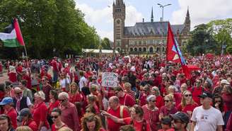 Manifestantes vestidos de vermelho marcharam do lado de fora do Palácio da Paz, sede do Tribunal Internacional de Justiça, em Haia.