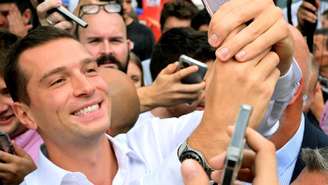 O presidente do partido Reunião Nacional, Jordan Bardella, faz selfies com o público em uma feira em Chalons-en-Champagne, no norte da França, em 7 de setembro de 2024.