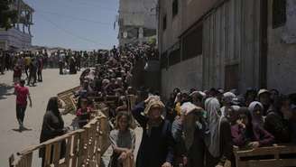 Palestinos fazem fila para receber sacos de farinha distribuídos pelo Programa Mundial de Alimentos (PMA) na Cidade de Gaza, norte da Faixa de Gaza, sábado, 12 de julho de 2025.