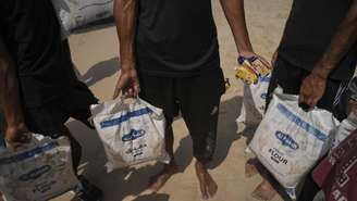 Palestinos recolhem mantimentos lançados no mar Mediterrâneo por via aérea sobre o centro de Gaza, na costa de Zawaida, Faixa de Gaza, terça-feira, 29 de julho de 2025.