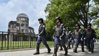 Policiais em equipamento anti-motim marcham em frente ao Domo da Bomba Atômica (ao fundo, à esquerda) enquanto protegem a área um dia antes das cerimônias que marcam o 80º aniversário do primeiro bombardeio atômico do mundo, na cidade de Hiroshima, província de Hiroshima, em 5 de agosto de 2025.