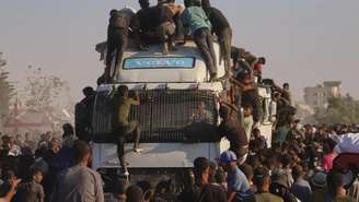 Palestinos sobem em um caminhão carregado de alimentos e ajuda humanitária, enquanto ele se move pelo corredor Morag, na Faixa de Gaza, em 4 de agosto de 2025. (Foto ilustrativa)