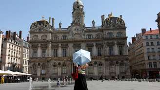 Uma mulher usa uma sombrinha para se proteger do calor em Lyon, no sudeste da França, onde são previstos até 42°C nesta quarta-feira, 13 de agosto de 2025.