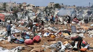 Palestinos observam os danos causados pelo ataque israelense a um acampamento de refugiados na região central da Faixa de Gaza, em 21 de agosto de 2025.