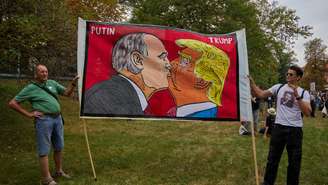 Em solidariedade à Ucrânia, manifestantes exibem uma faixa com caricaturas de Vladimir Putin e Donald Trump diante da embaixada russa em Praga, durante um protesto chamado "Vá para casa, Ivan!", que marcou o aniversário da invasão da Tchecoslováquia pelo Pacto de Varsóvia, em 1968. 21 de agosto de 2025