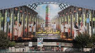 Cartaz em uma rua de Teerã com ilustrações de centrífugas iranianas e retratos de cientistas nucleares mortos em ataques de Israel, em 29 de agosto de 2025.