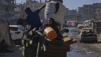 Palestinos deslocados, fugindo do norte da Faixa de Gaza, se movem com seus pertences por uma rua da cidade de Gaza, na quinta-feira (28)